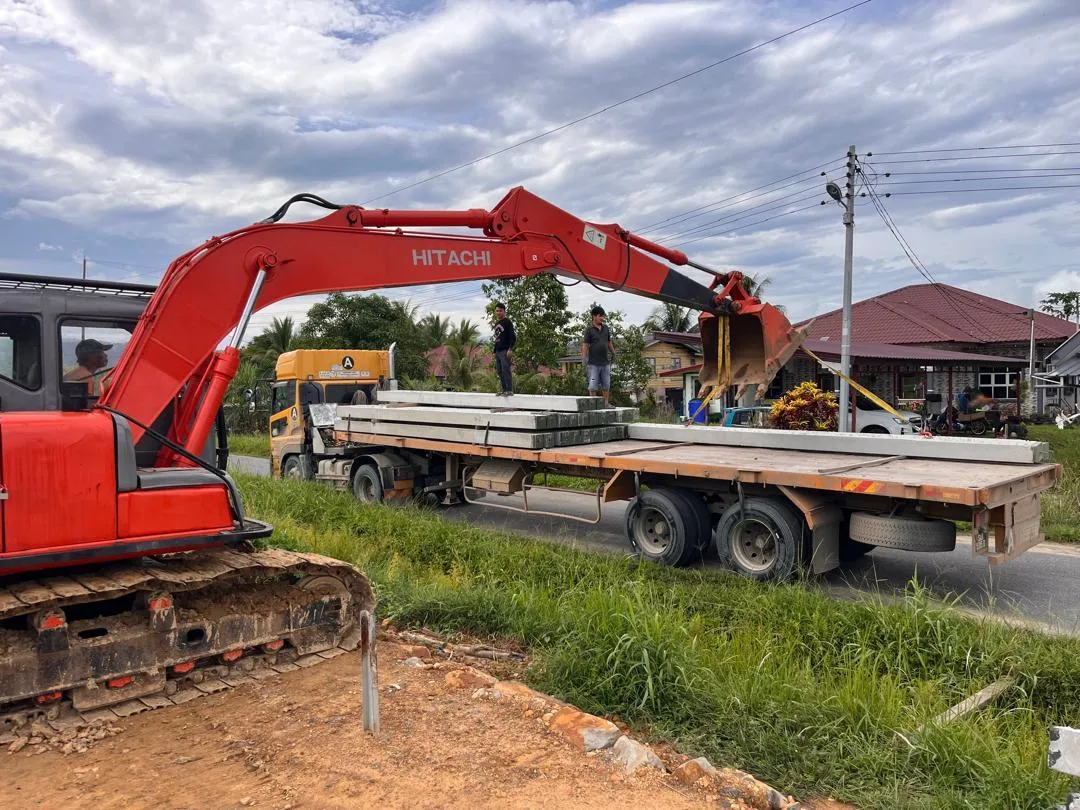 Excavator loading precast concrete slabs for transport